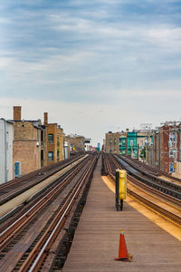 Railroad tracks in city against sky