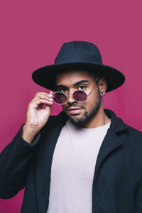 Portrait of young man wearing sunglasses against wall