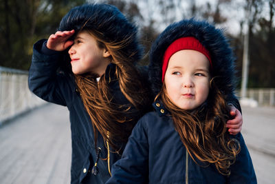 Siblings standing on footpath during winter