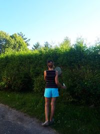 Full length of young woman standing against blue sky