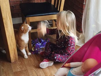 Girl playing with cat on hardwood floor