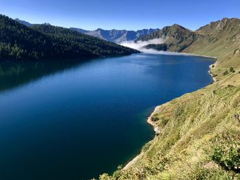 Scenic view of lake and mountains against clear blue sky