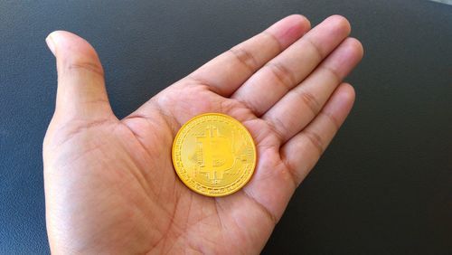 Cropped hand holding bitcoin over table