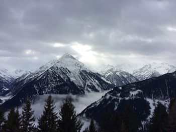 Scenic view of snow covered mountains against cloudy sky