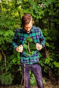 Mid adult man standing against trees in forest