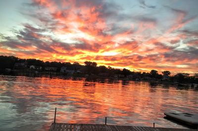 Scenic view of lake against cloudy sky at sunset