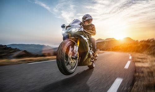 Man riding motorcycle on road against sky