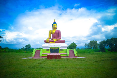 Buddha statue on field against sky