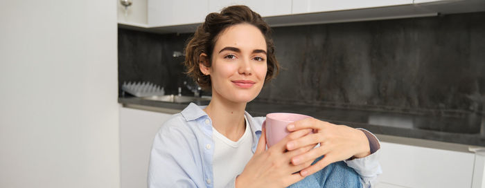 Portrait of young woman standing at home