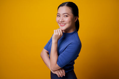 Portrait of a smiling young woman against yellow background