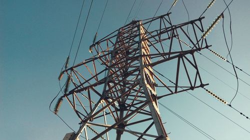 Low angle view of electricity pylon against clear blue sky