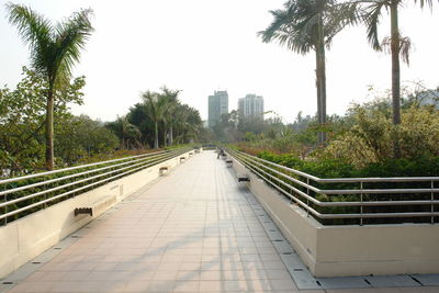 Road leading towards city against clear sky