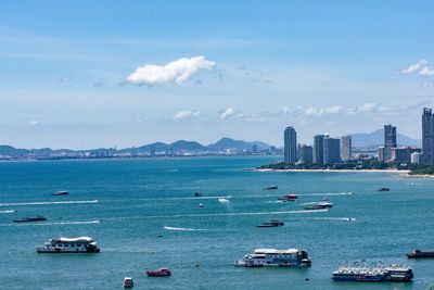 Ships sailing on sea by city against sky