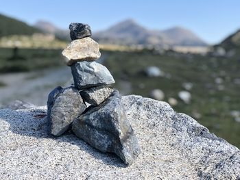 Stack of stones on rock against sky