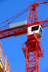 Low angle view of crane against clear blue sky