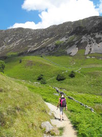 Rear view of woman walking on land by mountain