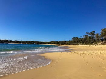 Scenic view of beach against clear blue sky