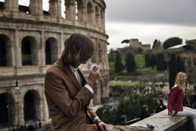 Man smoking cigarette against coliseum