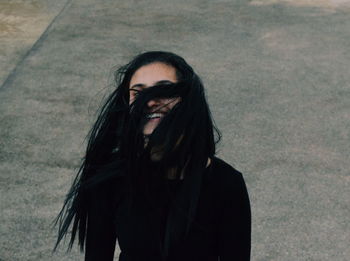 Smiling young woman standing with tousled hair