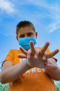 Low angle view of boy with hands clasped standing against sky