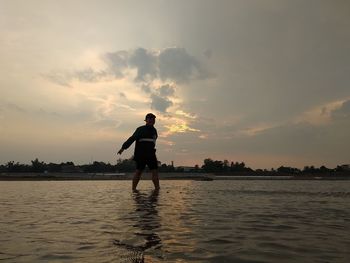 Silhouette man standing on beach against sky during sunset