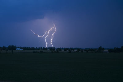 Lightning over field against sky at night