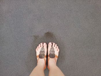 Low section of woman standing on sand