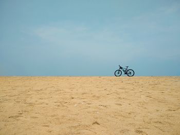 Cycle riding on sand at beach against sky, poovar golden sand beach, thiruvananthapuram