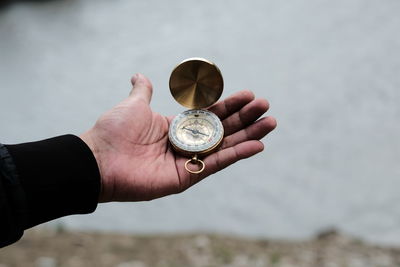 Close-up of hand holding clock against blurred background