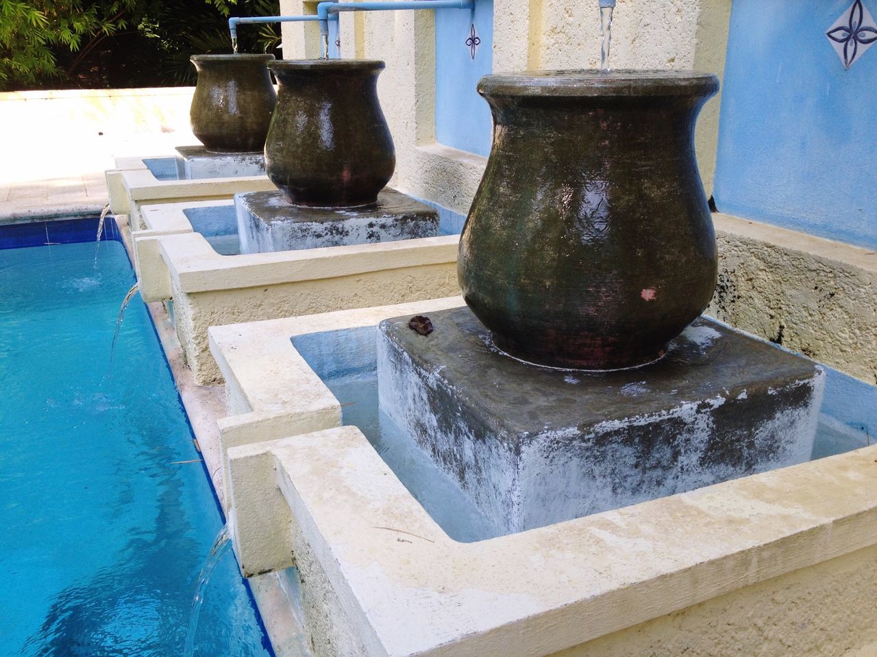 built structure, architecture, blue, water, building exterior, high angle view, sunlight, fountain, day, outdoors, old, metal, no people, swimming pool, wall - building feature, weathered, railing, stone material, reflection, shadow