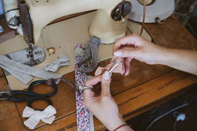 Cropped hand of woman using sewing machine