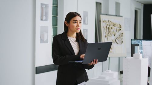 Portrait of young businesswoman using laptop at office