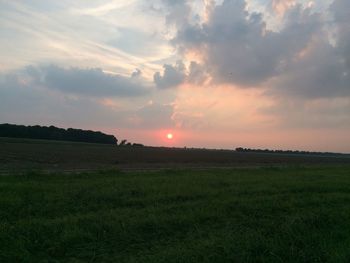 Scenic view of grassy field against sky during sunset