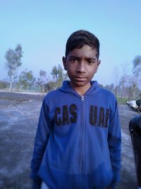 Portrait of boy standing against blue sky