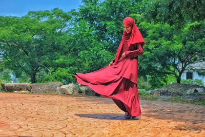 Young woman with red umbrella against trees