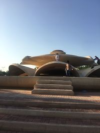 Low angle view of people on staircase against clear sky