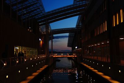 Illuminated bridge over river amidst buildings in city at night