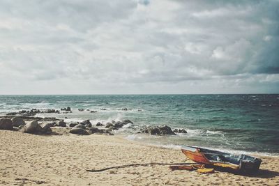 View of calm beach against cloudy sky