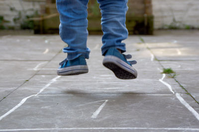 Low section of boy playing hopscotch on pavement