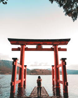 Rear view of woman standing at torii gate