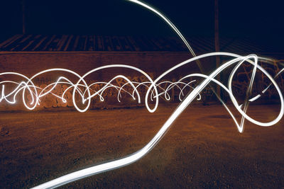 Light trails on bridge against sky at night