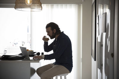 Male freelancer drinking coffee while working at home