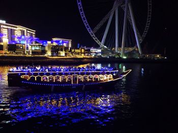 Illuminated boats moored in river at night