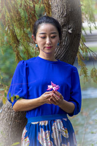 Full length of woman standing on tree trunk