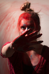 Portrait of woman with powder color on palm of hand standing against wall