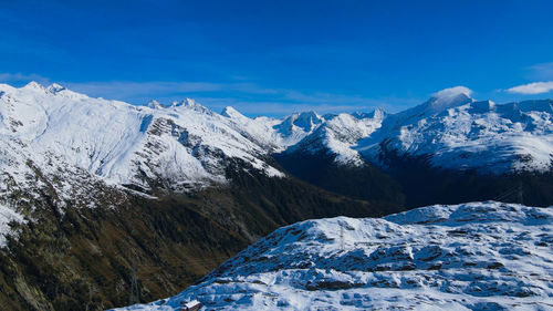 Scenic view of snowcapped mountains against blue sky