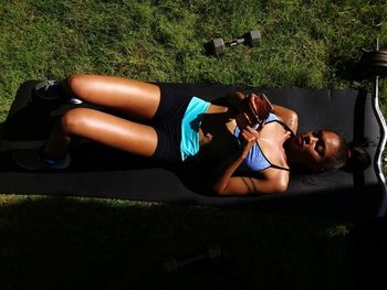 Directly above shot of woman using phone while lying on exercise mat