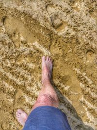 Low section of man standing on sand