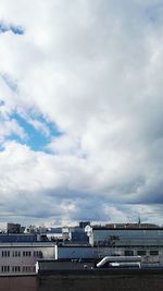 Bridge over river in city against cloudy sky