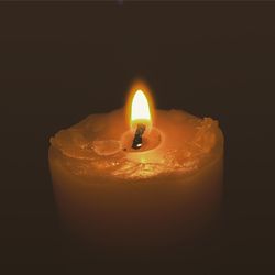 Close-up of lit candle in dark room